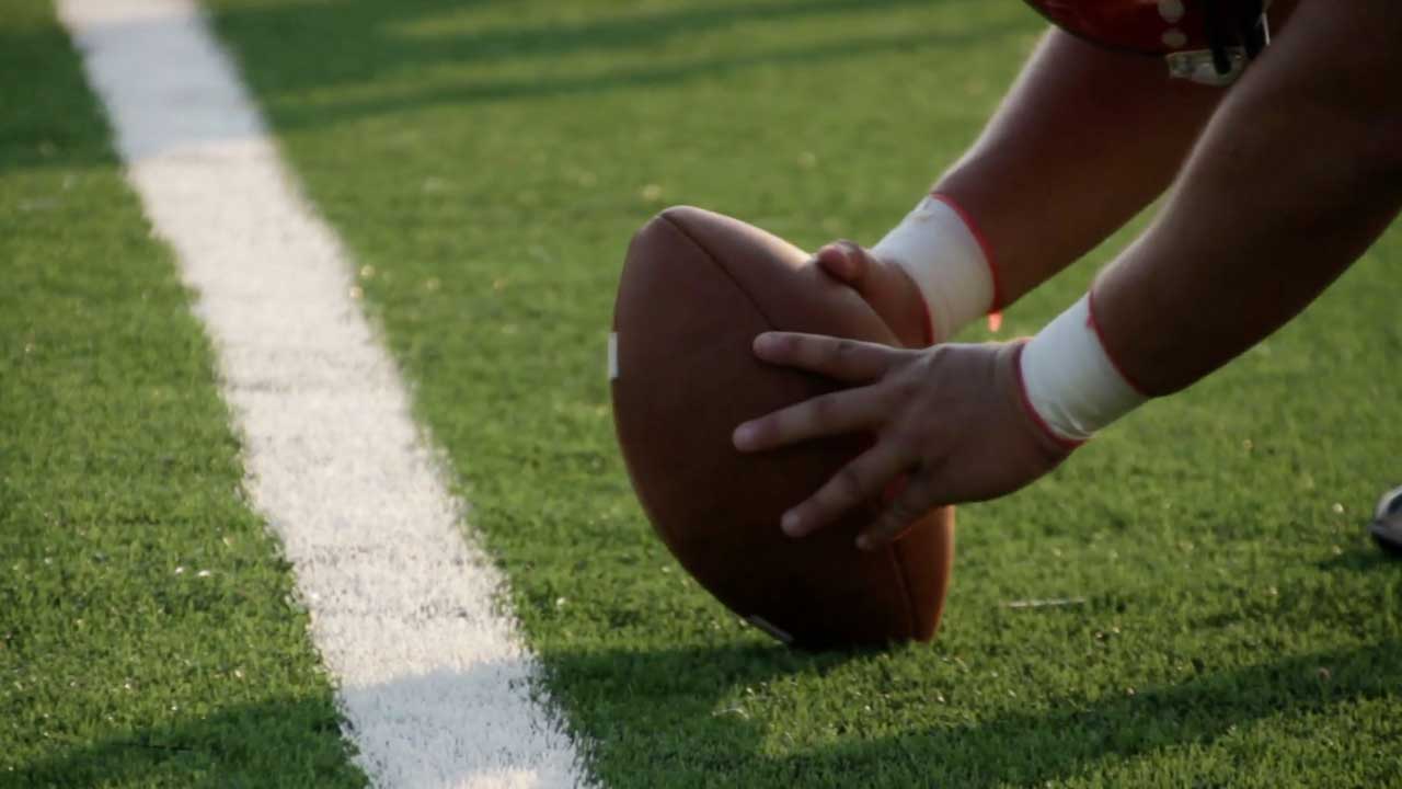 Player holds the football at the line on a field