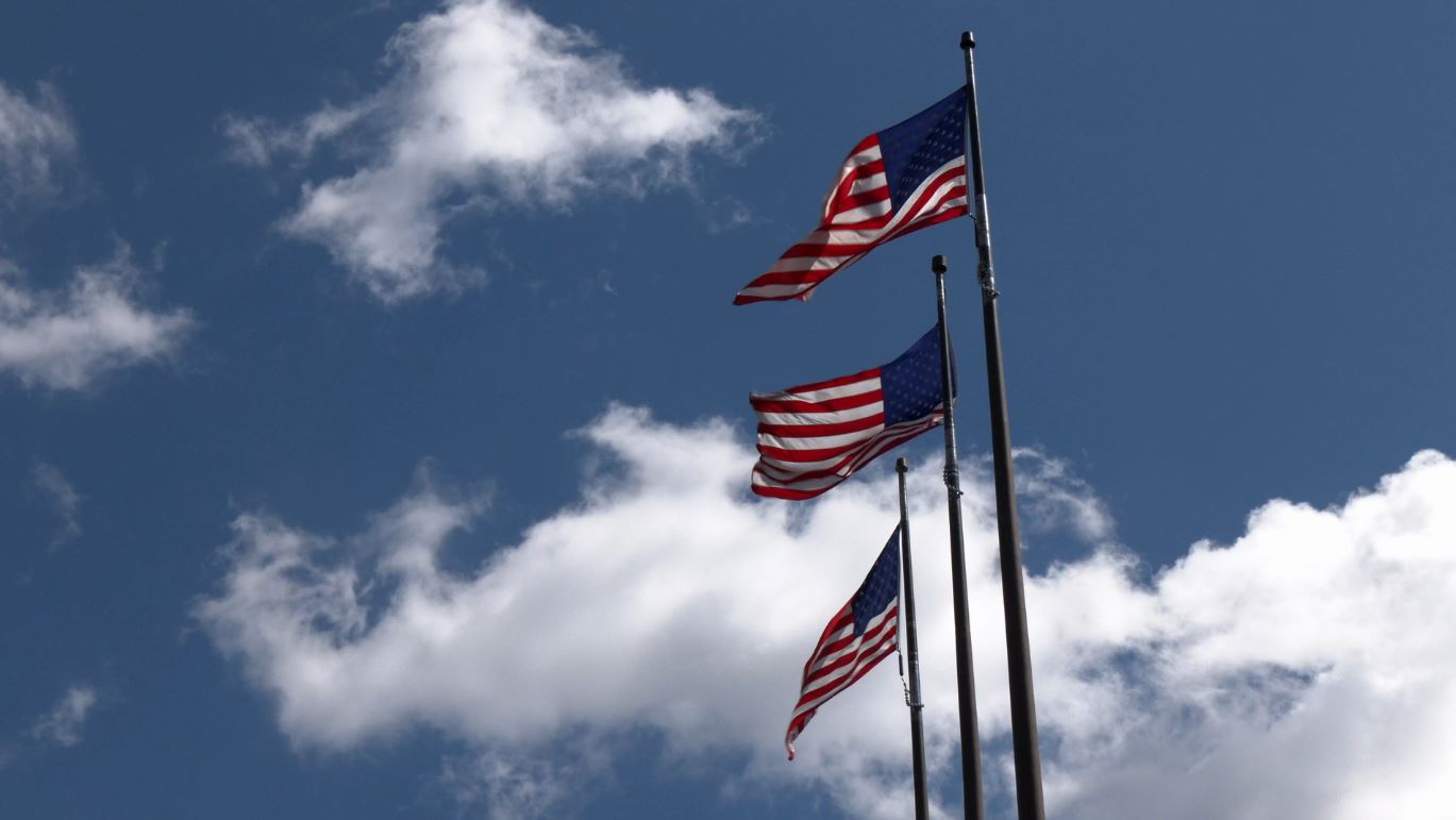 Three American flags wave in the wind