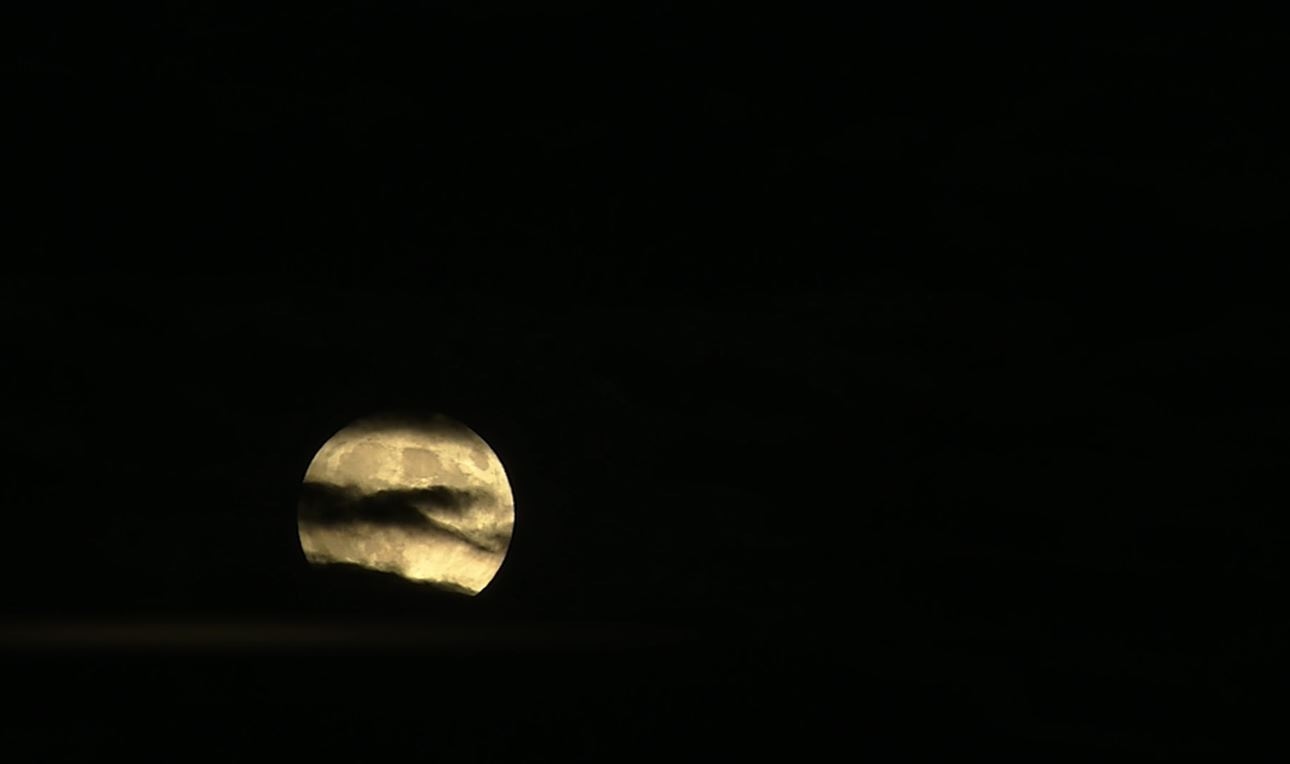 The moon behind wispy clouds